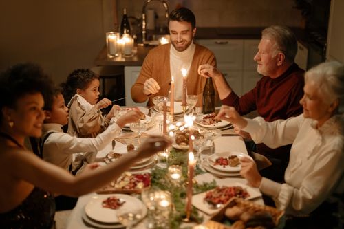 Free Family enjoying a festive dinner together indoors with warm candlelight. Stock Photo