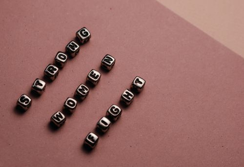 Free Close-up of beads spelling 'Strong Women Fight' on a brown background. Stock Photo