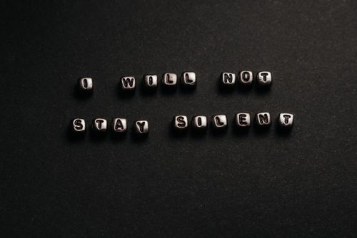 Free Black beads spell out 'I will not stay silent.' A powerful and inspirational message against a dark background. Stock Photo