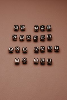 Inspirational quote 'Be the change you want to see' with letter beads on a neutral background.