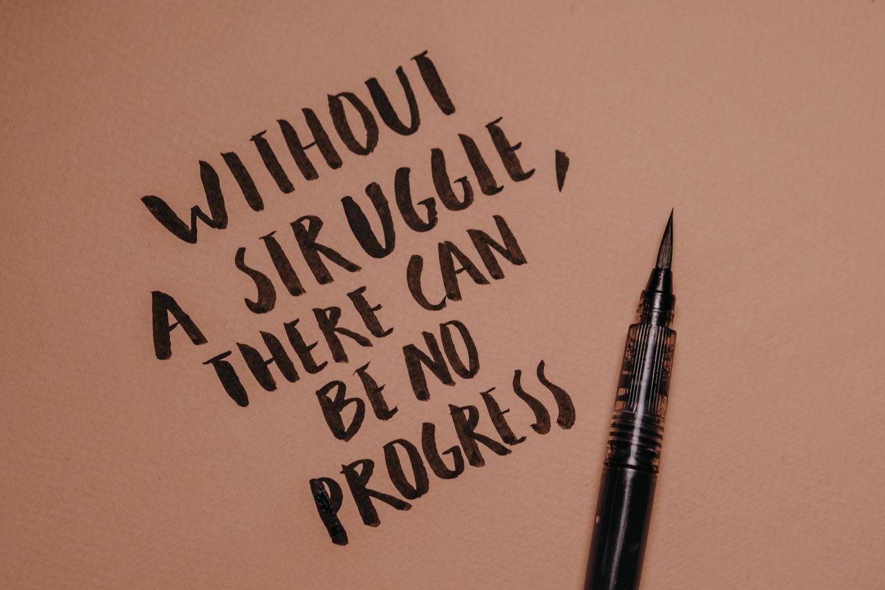 handwritten motivational quote using a brush pen on a textured backgro