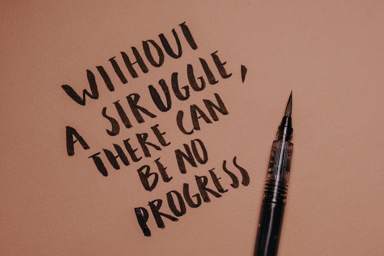 A Close-Up Shot Of A Handwritten Quote Beside A Brush Pen