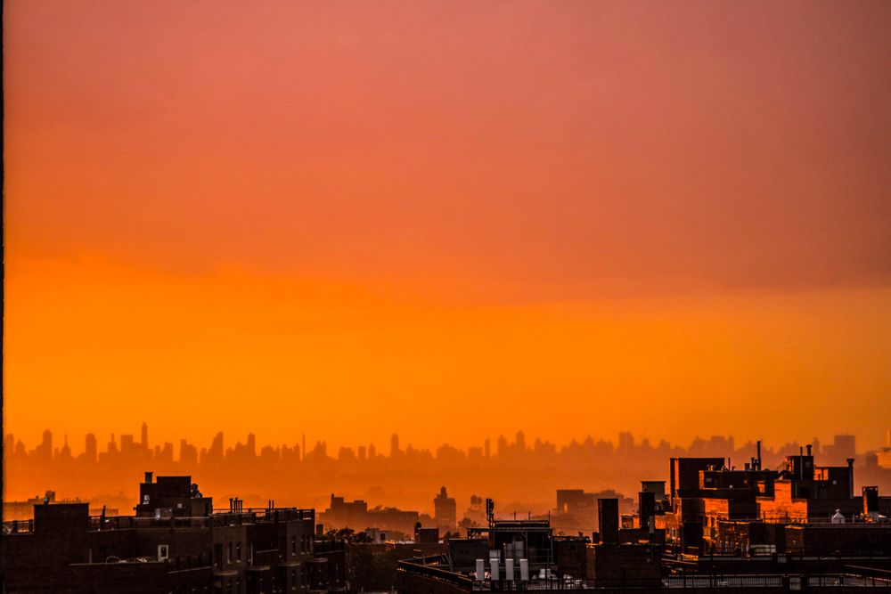 Capture the beauty of an urban skyline at sunset with warm orange hues and silhouetted buildings.