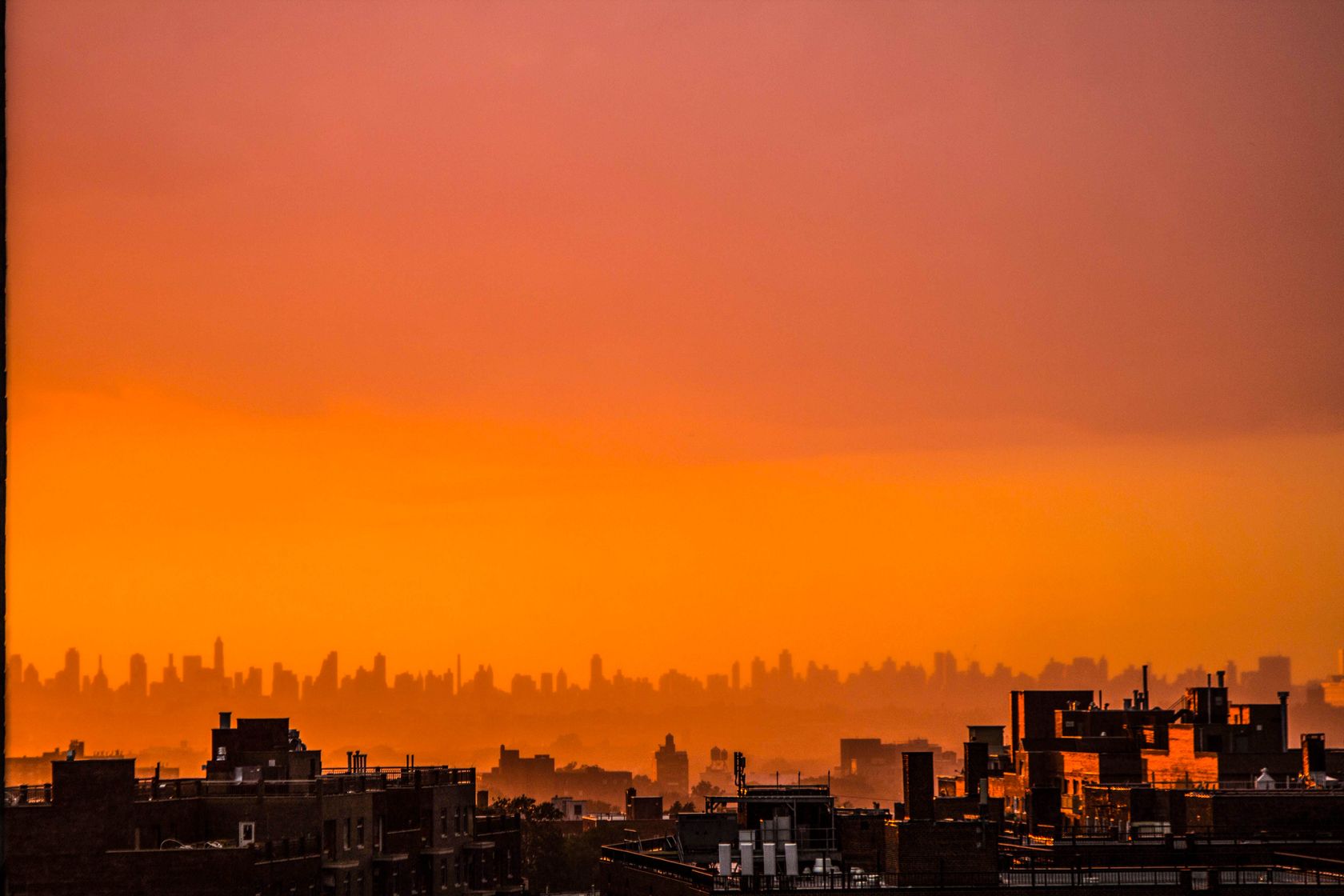 Capture the beauty of an urban skyline at sunset with warm orange hues and silhouetted buildings.