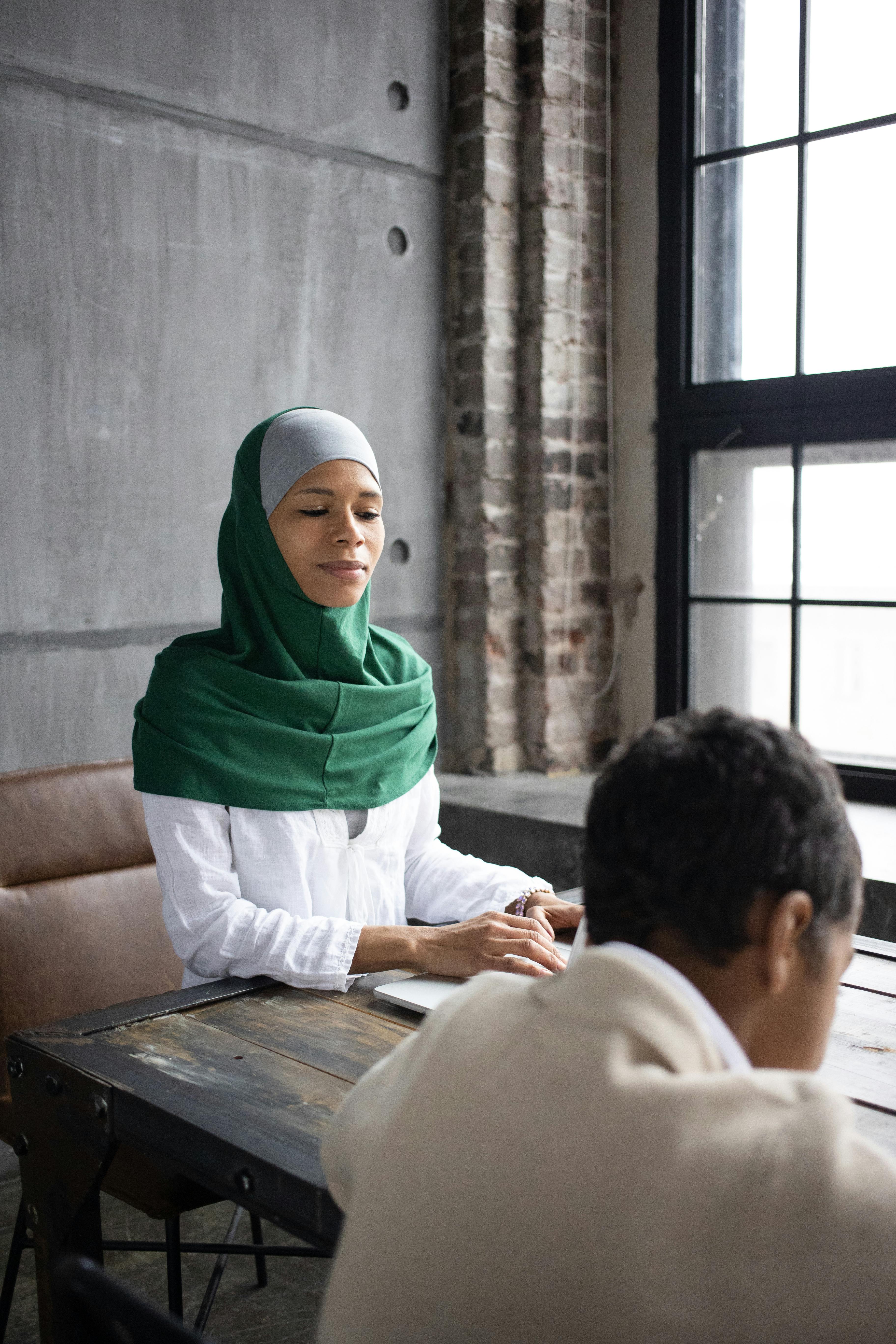 arabian woman preparing presentation with son while sitting at table near window