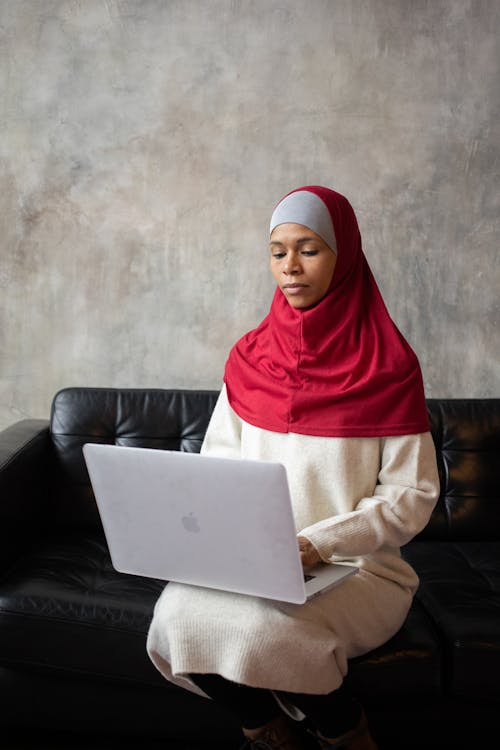 Wanita Hijab Merah Duduk Di Sofa Kulit Hitam