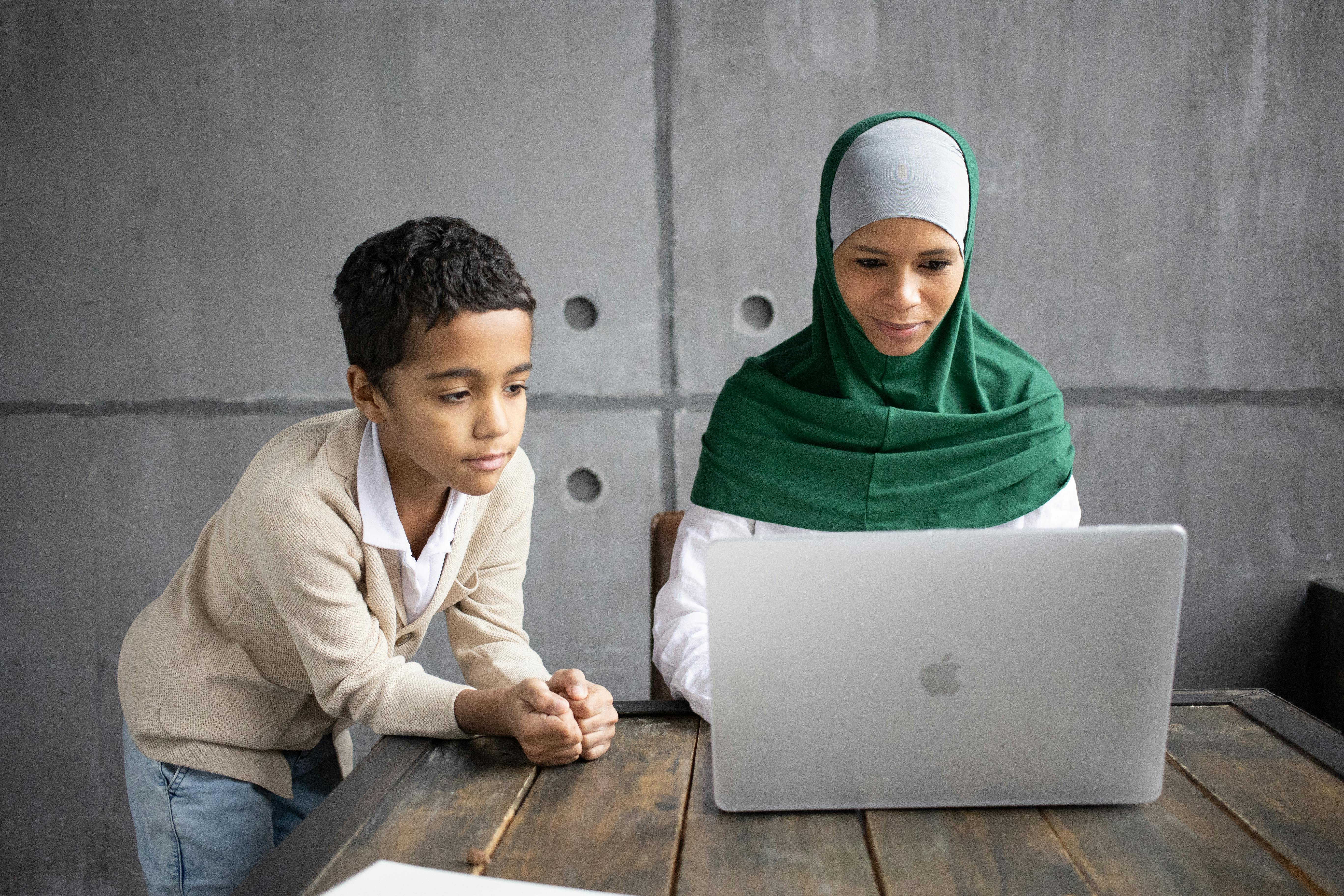 arabian woman and son watching videos on portable laptop at home