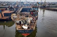 From above of aged rusty ship with rubbish moored in abandoned port in cloudy day in daylight