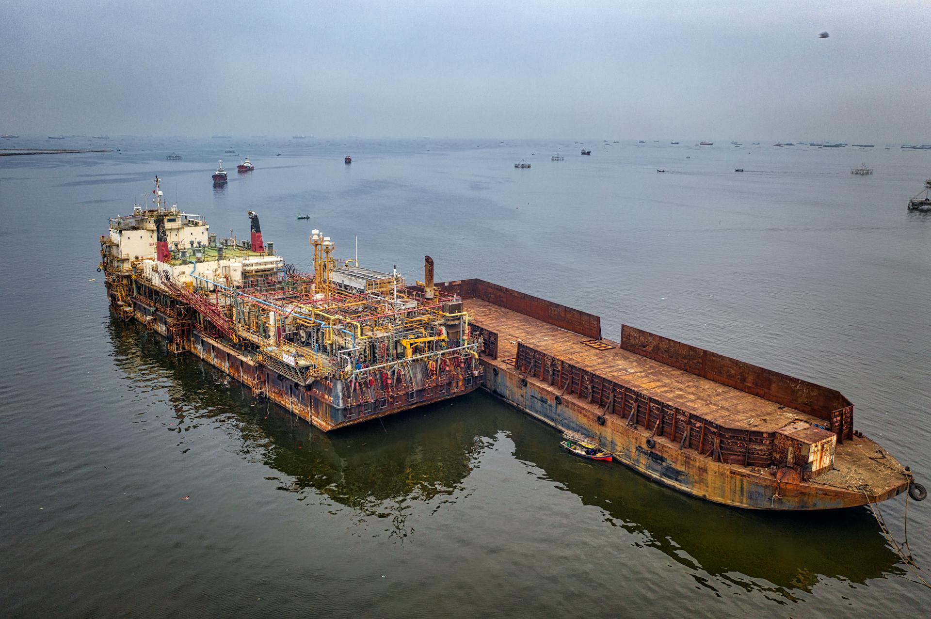 High angle of aged abandoned cargo ship floating in calm water of ocean in daytime
