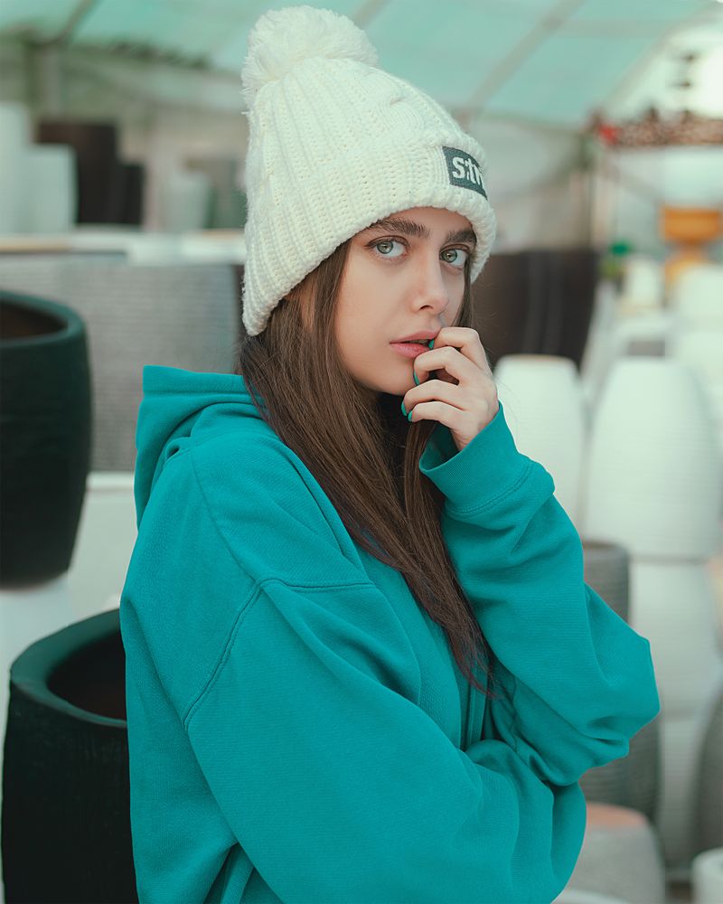 Woman in a teal hoodie and white knit cap