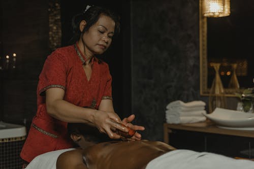 Woman in Red Shirt Using Massage Oil in Massage Room