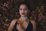 一位优雅时尚的女子躺在秋叶上，展现珠宝与风采