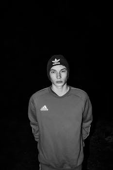 Black and white portrait of a young man in a beanie and sweatshirt, looking directly at the camera.