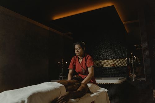 Free Peaceful massage session with a female masseuse attending to a client in dim ambiance. Stock Photo