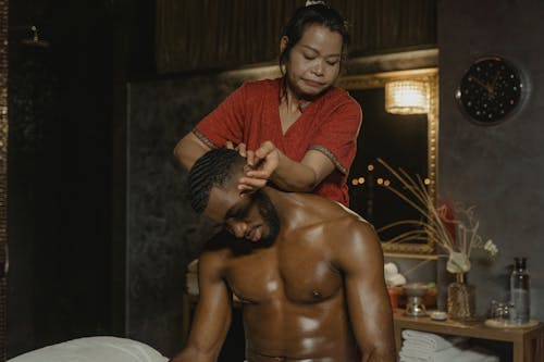 Free Woman Massaging a Shirtless Man on Head While Sitting Stock Photo