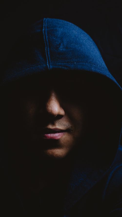 Free Moody portrait of a man with a hood, partially hidden in shadows, conveying mystery and depth. Stock Photo