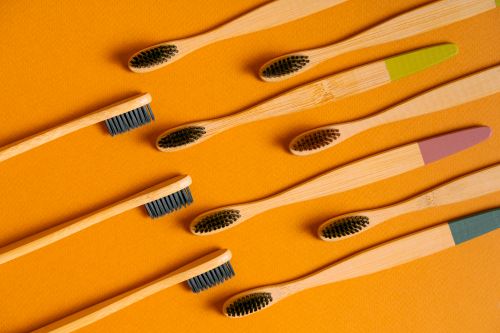 Free Flatlay of bamboo toothbrushes on vibrant orange, highlighting eco-friendly dental care. Stock Photo