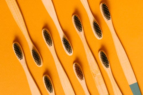 Free Close-Up Shot of Wooden Toothbrushes on an Orange Surface Stock Photo