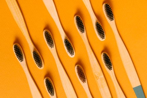 Free Close-up of bamboo toothbrushes on a vibrant orange surface highlighting eco-friendly dental care. Stock Photo