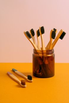 Aesthetic display of eco-friendly wooden toothbrushes in a glass jar on a colorful background.