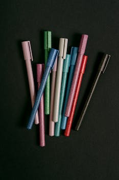 A collection of colorful pens arranged on a dark surface, ideal for school supplies and stationery themes.