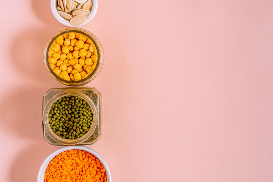 Assorted legumes like lentils and chickpeas next to a bowl of dry steel-cut oats - energy boosting superfoods list Assorted legumes like lentils and chickpeas next to a bowl of dry steel-cut oats - energy boosting superfoods list