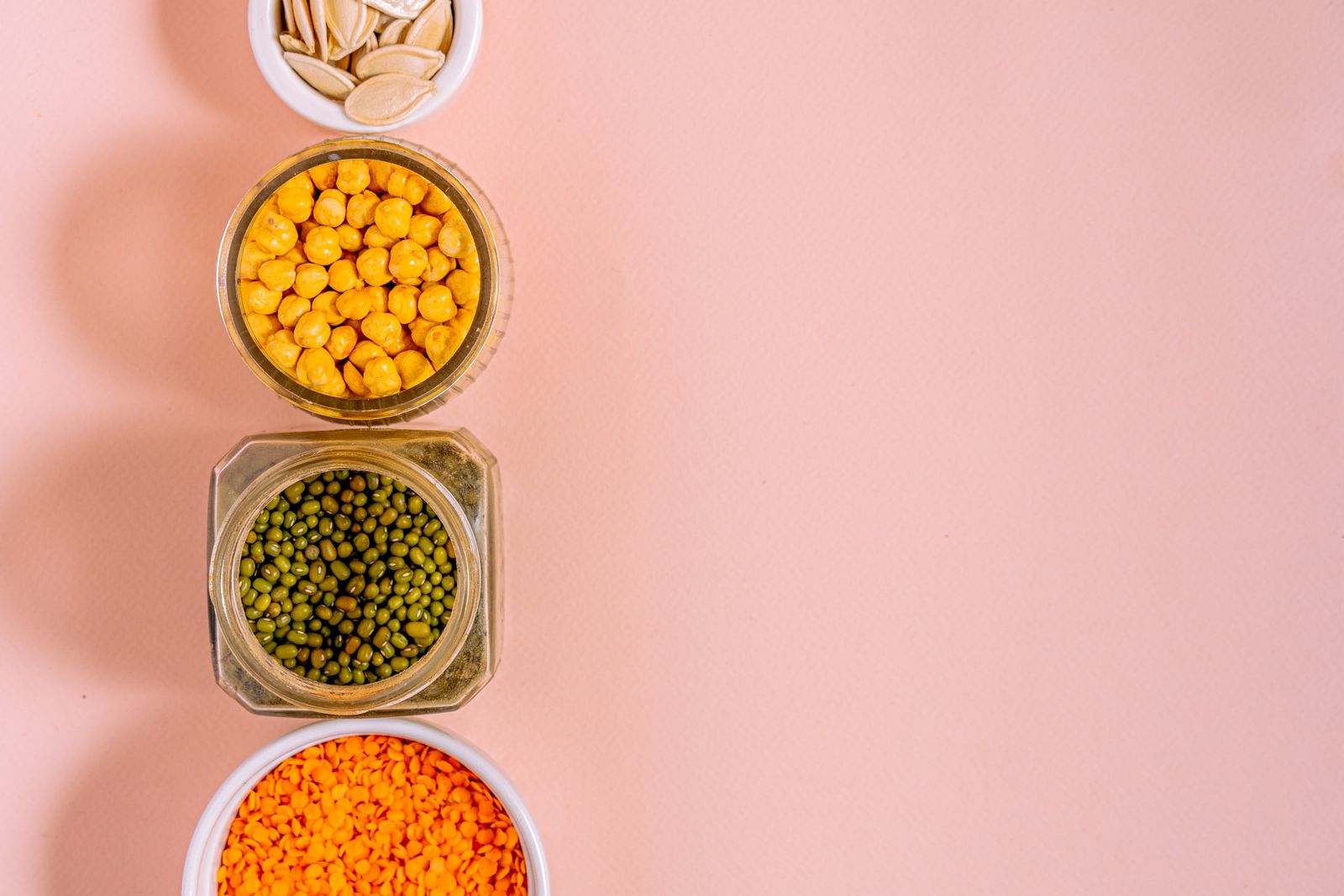 Flat lay of chickpeas, lentils, mung beans, and pumpkin seeds representing plant based protein sources
