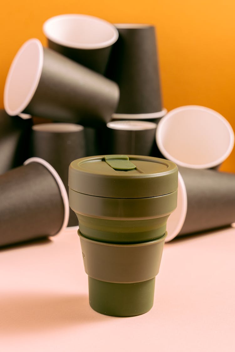 Dark Green Reusable Cup With Paper Cups At The Background