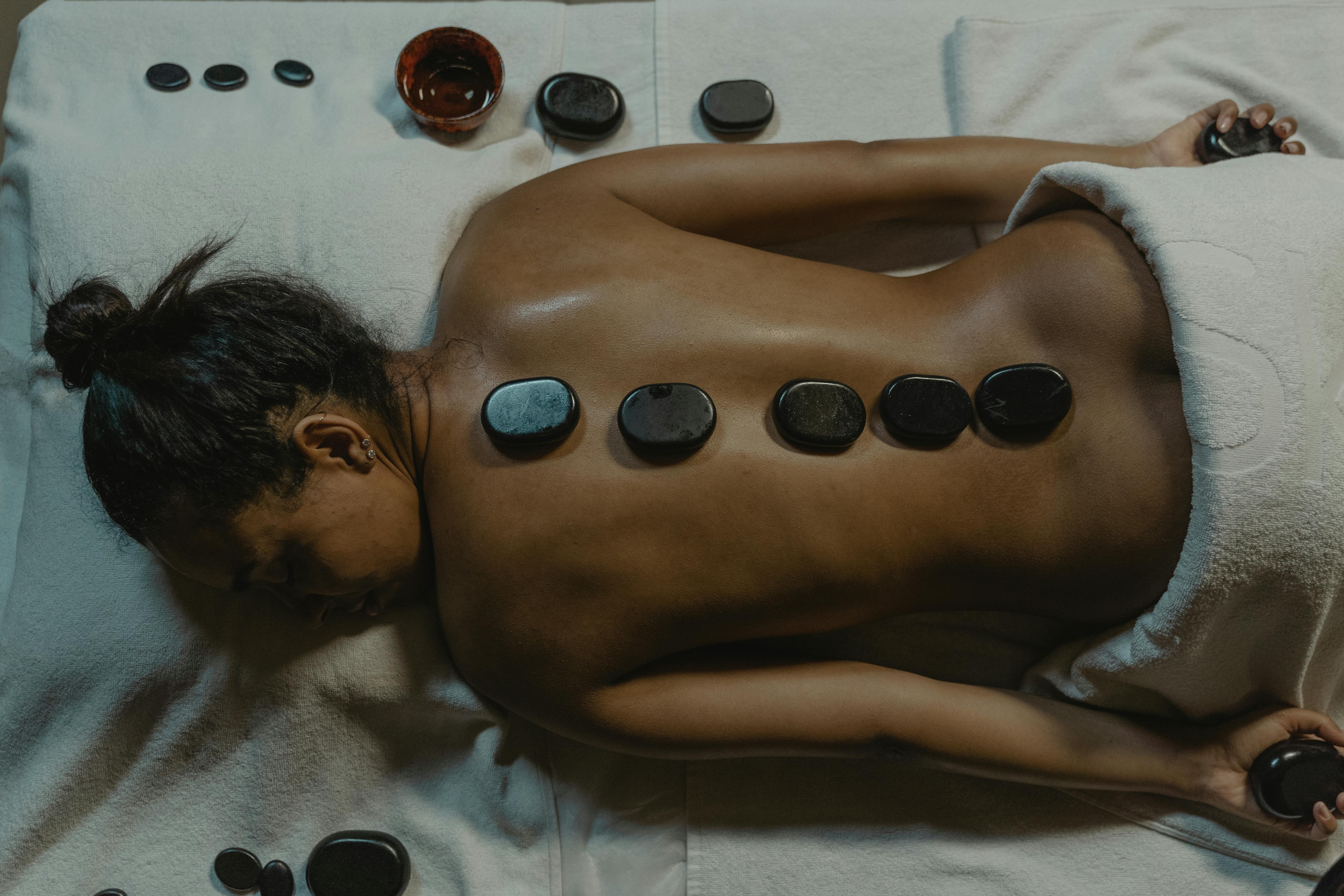 naked woman with hot stone massage on her back