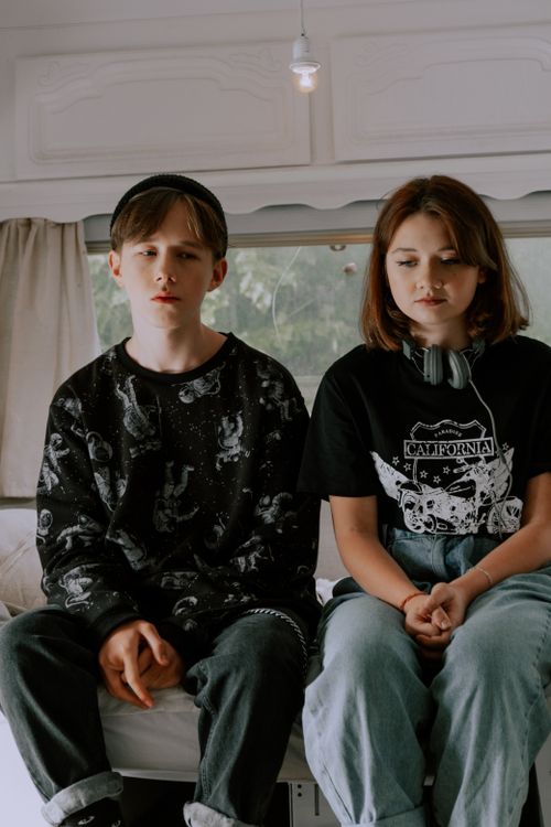 Free Teenagers in casual wear sitting together indoors with serious expressions. Stock Photo
