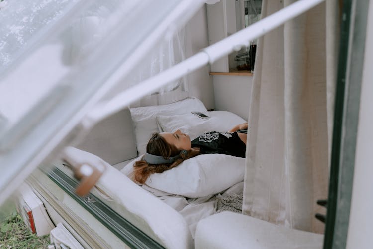 Woman With Headphones Lying On The Bed