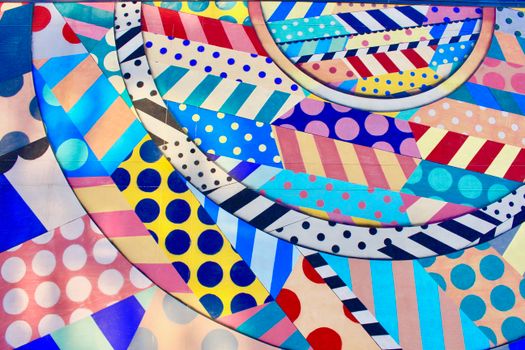 A vibrant and colorful abstract design featuring geometric patterns, stripes, and polka dots.