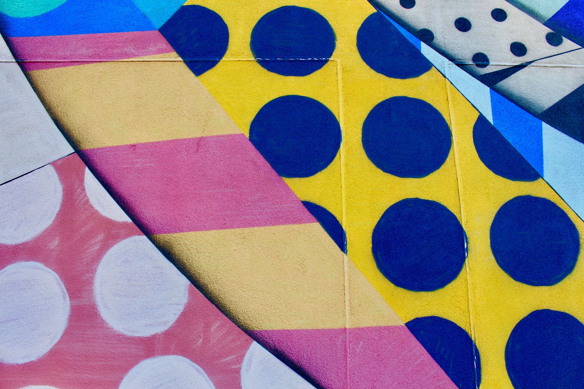 Vibrant geometric wall mural with bold colors and patterns featuring circles and stripes.
