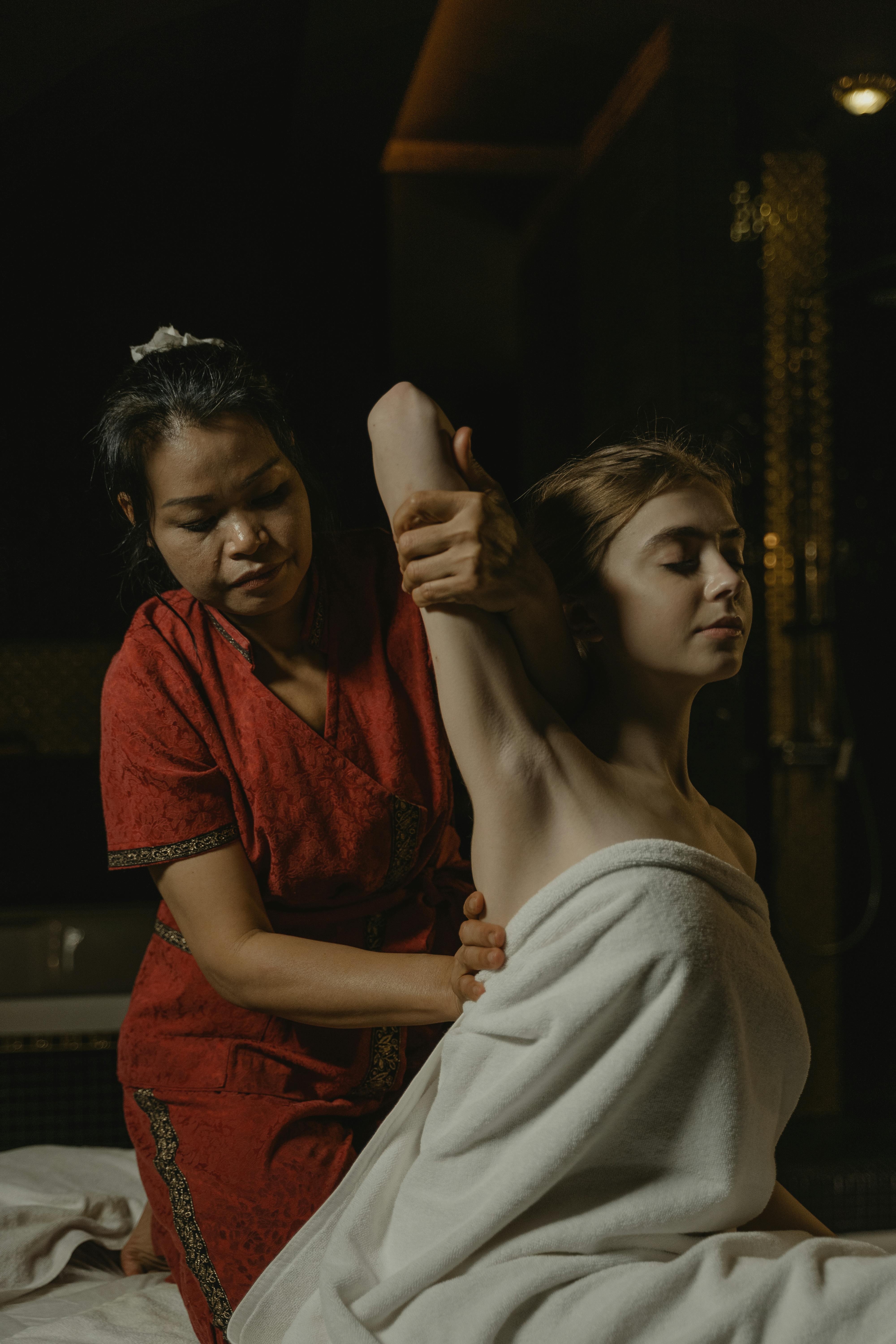 woman in red dress massaging a woman s back in white towel