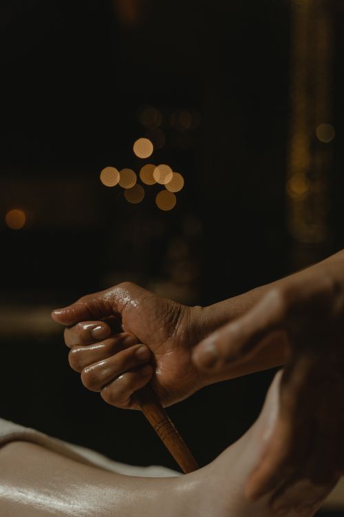 Free A detailed view of a hand using a wooden stick during a foot massage treatment. Stock Photo