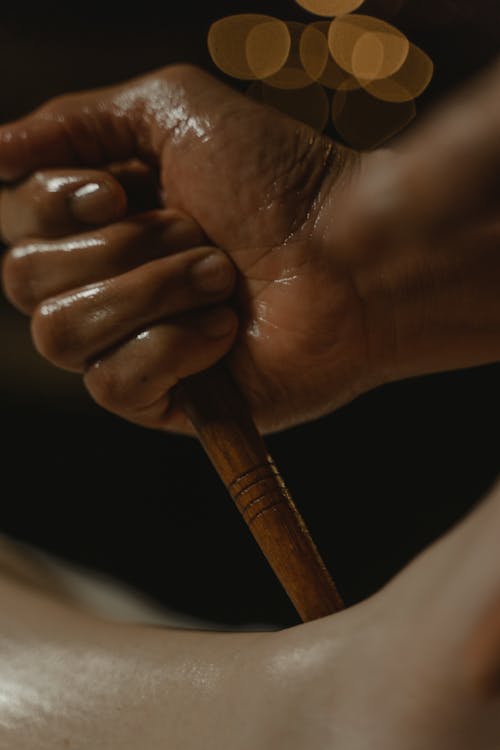 Oily Hands of a Person Holding Brown Wooden Stick