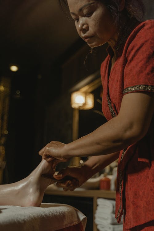Free Woman in Red Massaging a Person's Barefoot Stock Photo