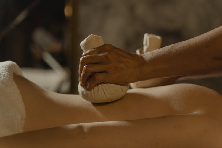 Person's Hands Massaging A Person's Bare Back With Fabric Balls