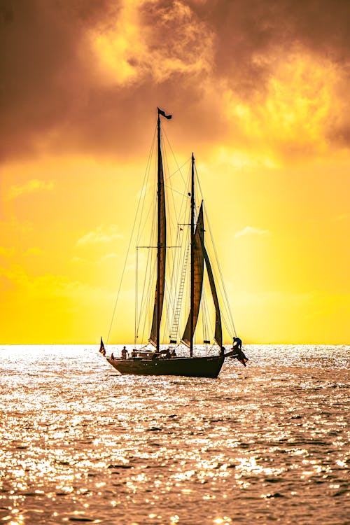 Free Silhouette of a Sailboat on the Sea during Sunset Stock Photo