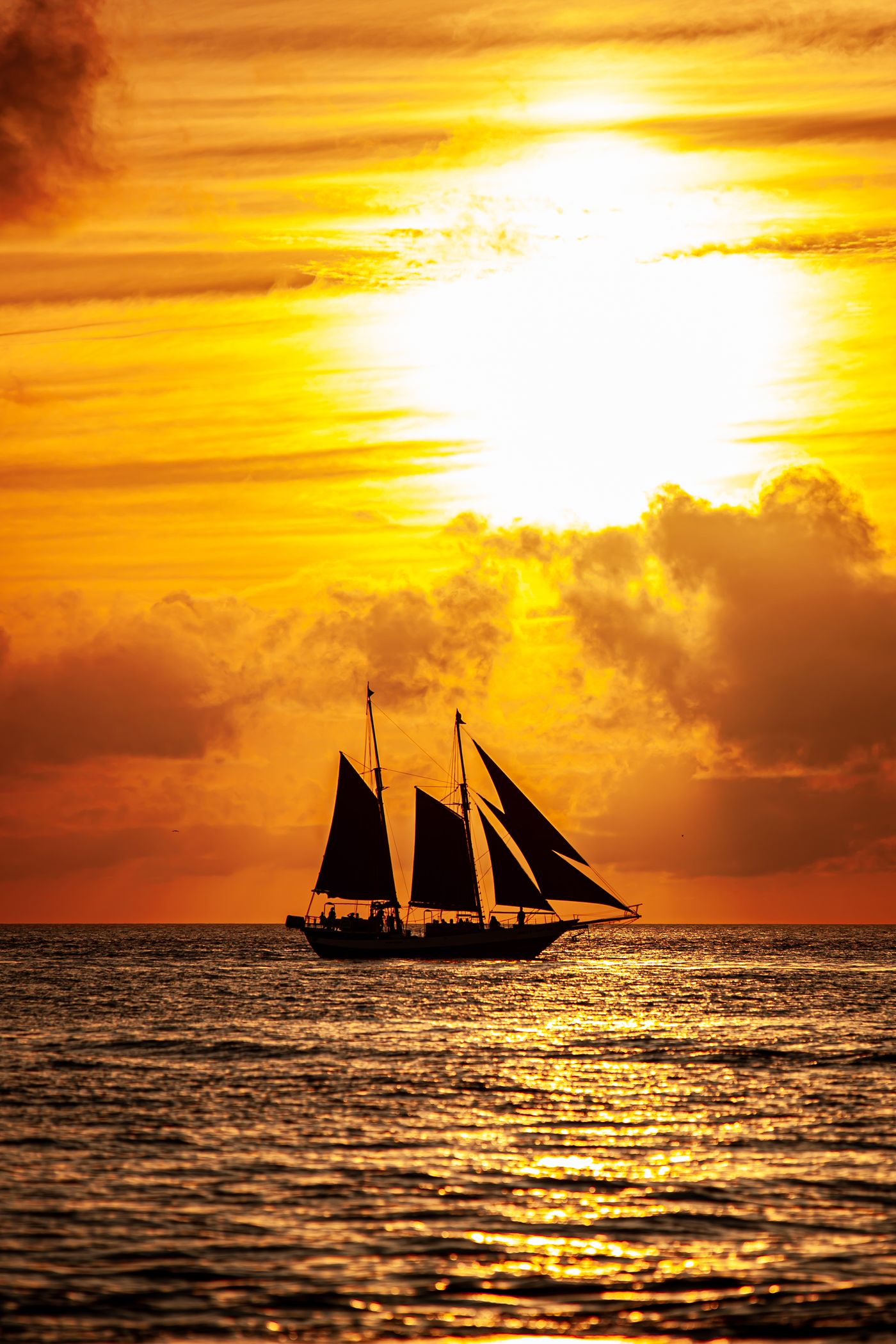 Sailboat silhouetted against a vivid ocean sunset