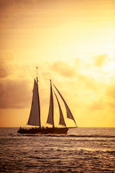 A schooner sails against a vibrant sunset, capturing the essence of maritime adventure.