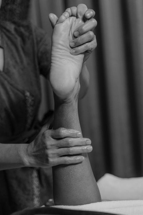 Grayscale Photo of a Person Doing a Massage on a Foot