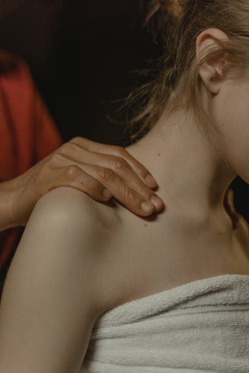 Free Close-Up Shot of a Person Massaging the Shoulder of an Another Person Stock Photo