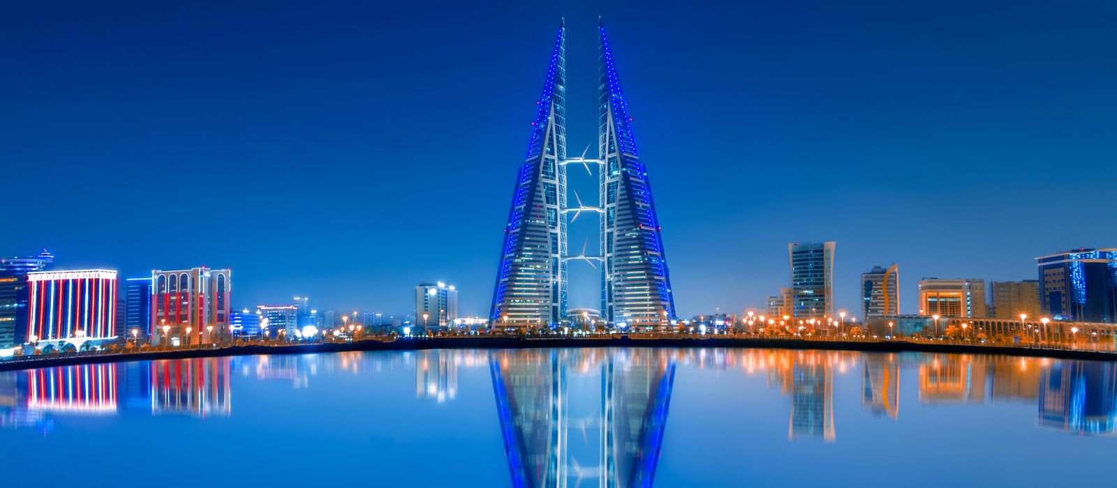 Stunning night view of Bahrain World Trade Center with clear water reflections and modern skyline. — flights from London to Manama