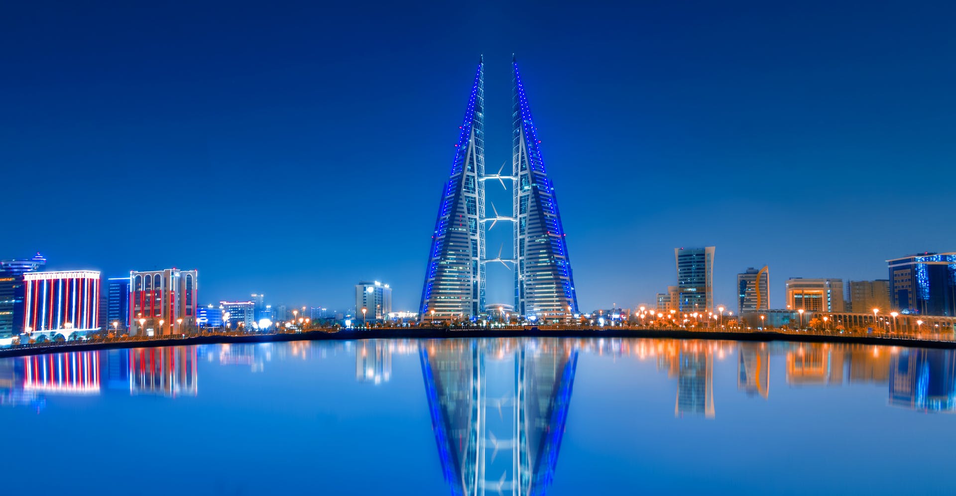 Stunning night view of Bahrain World Trade Center with clear water reflections and modern skyline.