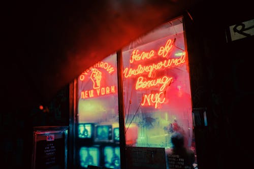 Exterior of shop with shiny neon inscriptions and vintage TV sets on street in late evening