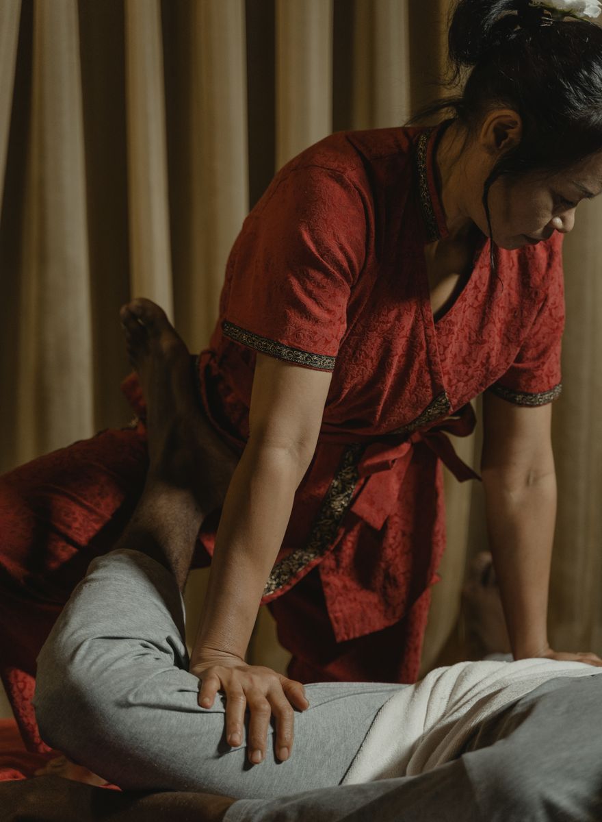 Traditional Thai massage Fulham — therapist applying pressure along the leg on a treatment table