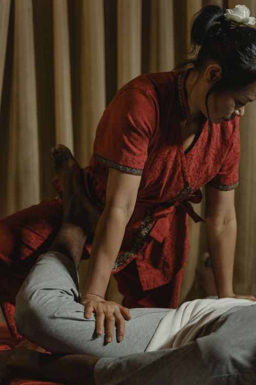 Free Professional Thai massage session with therapist applying pressure on client's leg for relaxation. Stock Photo