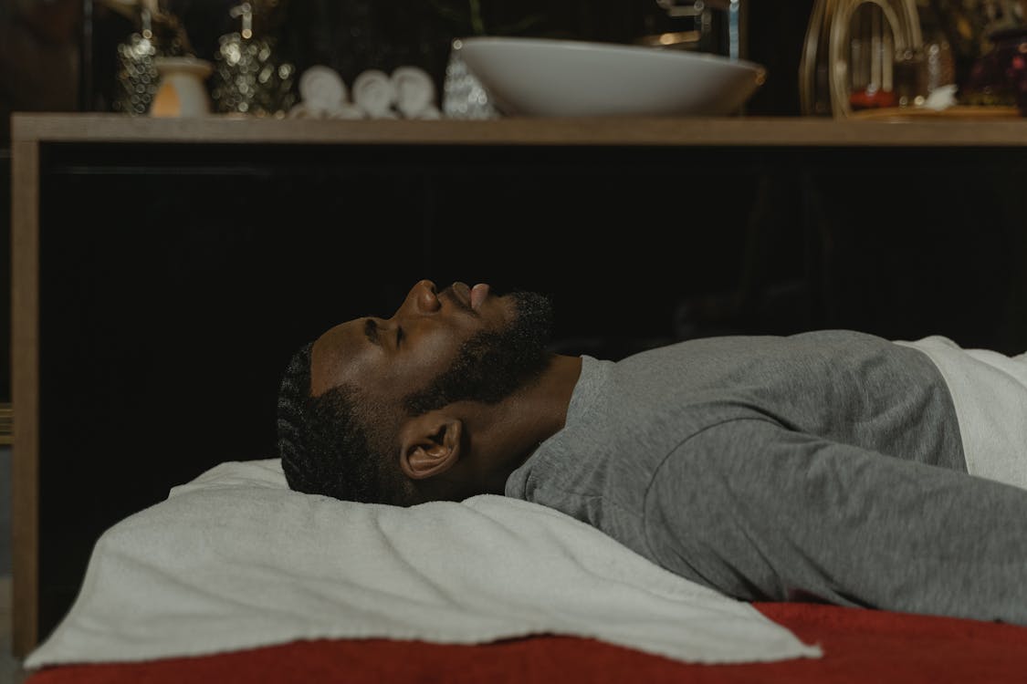 Man in Gray Sweater Lying on Bed with Eyes Closed