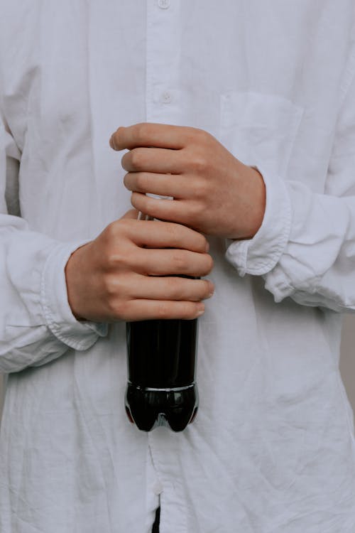 A Person in White Long Sleeves Holding a Soda Drink